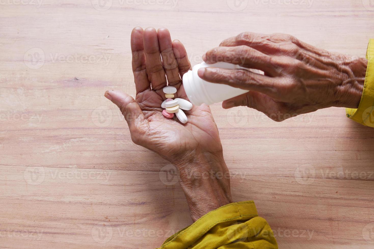 Cerca de píldoras y cápsulas en la mano de mujeres mayores foto