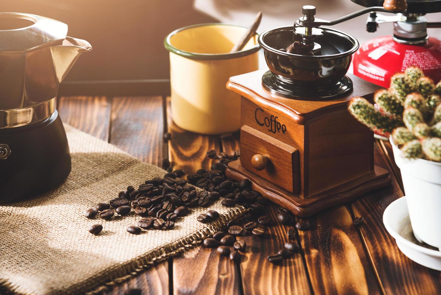 taza de café, granos tostados e ingredientes para hacer café y accesorios en el fondo de madera de la mesa. concepto de fabricación de café foto