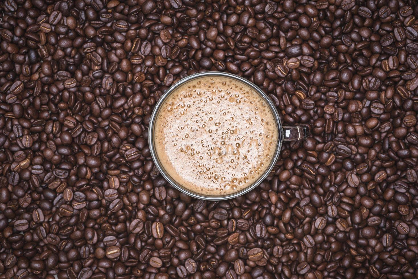 Cup of cappuccino placed in a plate of coffee beans, with Roasted Full frame coffee beans background photo