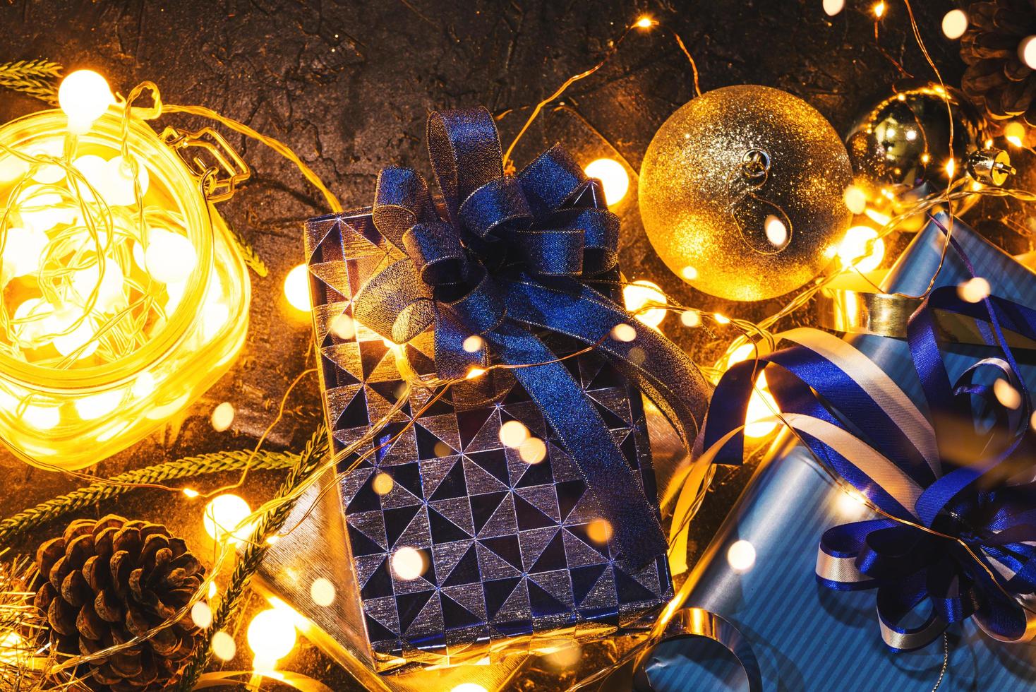 Christmas gift with blue ribbon and Christmas decoration balls on abstract bokeh black background with copy space and decorative LED lights. Merry Christmas and New Year. photo