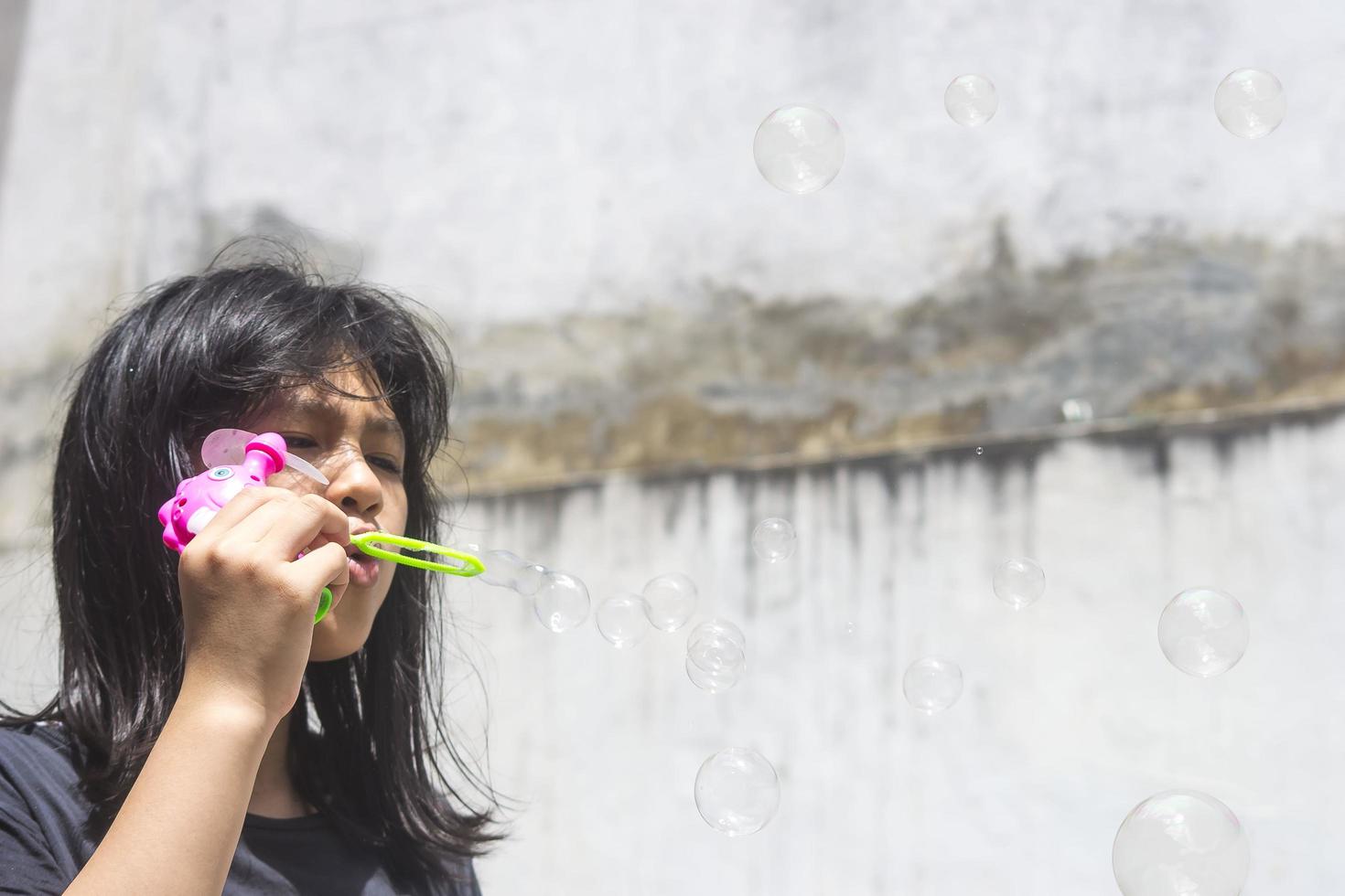 una niña que sostiene una máquina de hacer burbujas y las sopla. foto