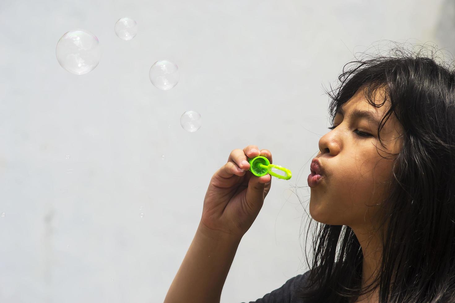 una niña que sostiene una máquina de hacer burbujas y las sopla. foto