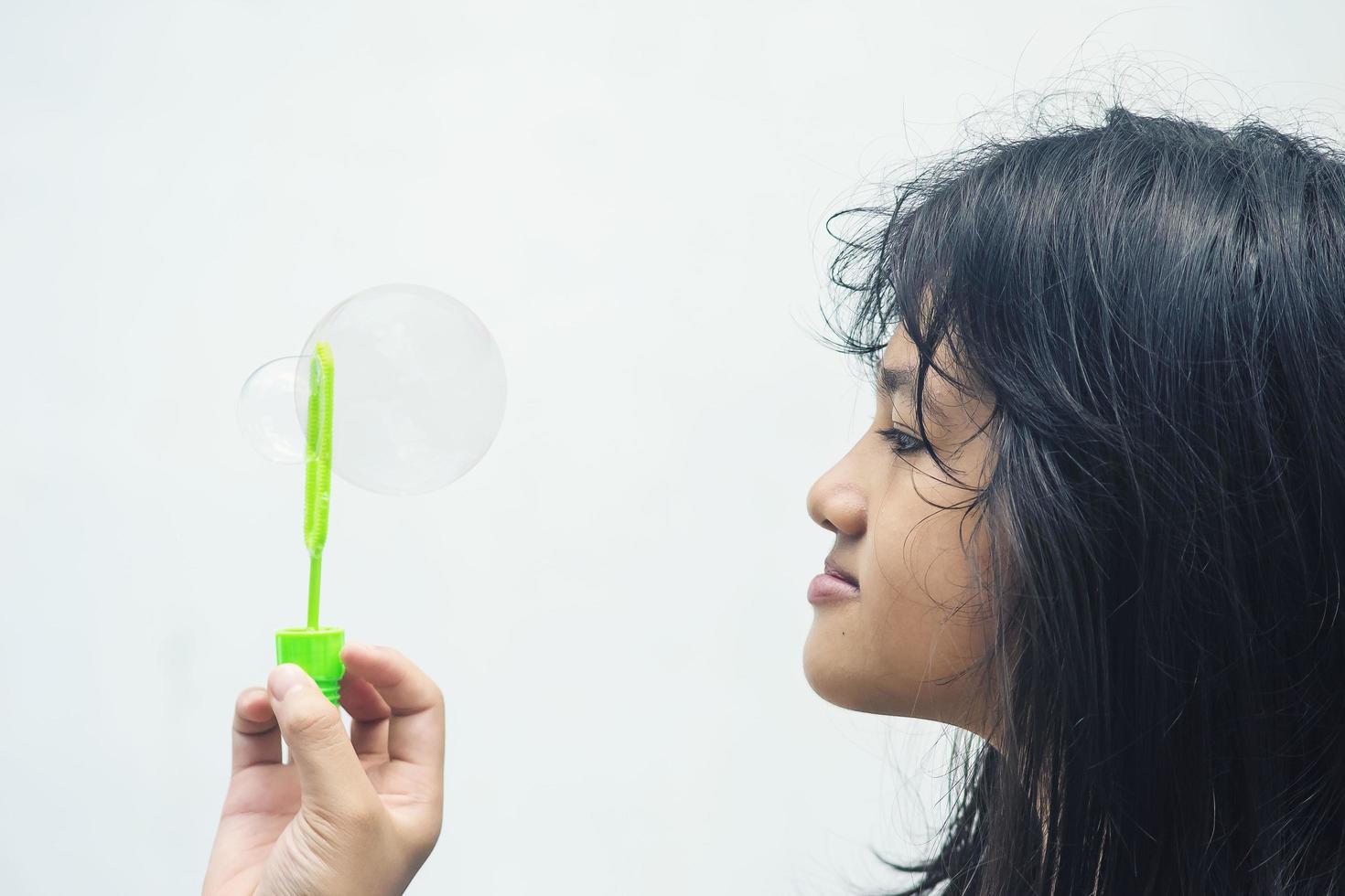 A girl holding a bubble maker and blowing them out. photo