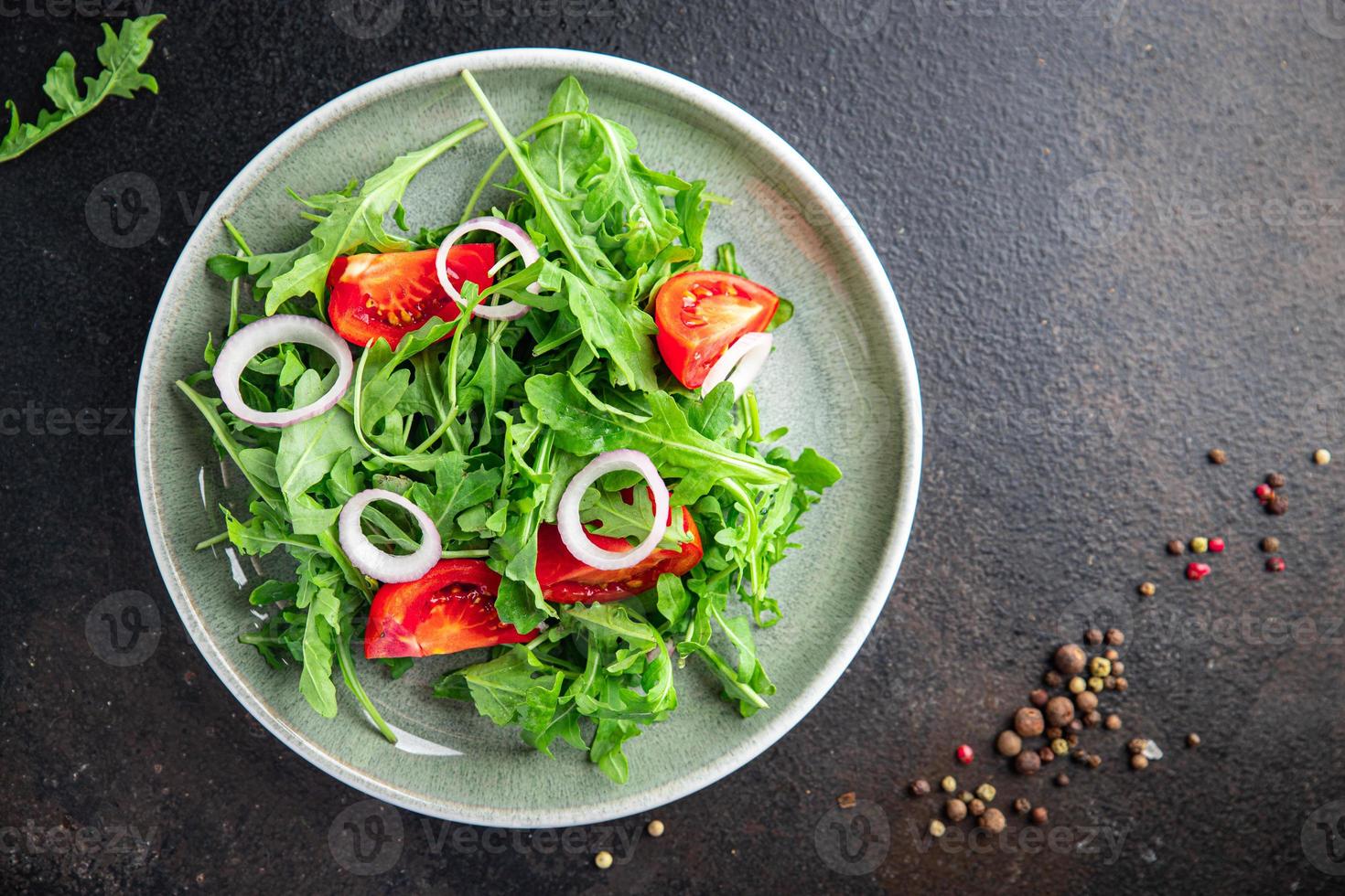 Ensalada de verduras frescas rúcula, tomate, plato de cebolla, comida, bocadillo en la mesa, espacio de copia, fondo de alimentos foto