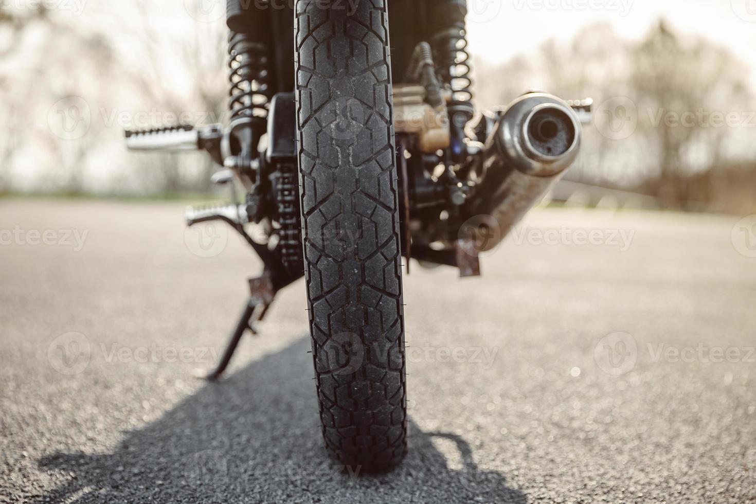 Wheel and exhaust pipe of motorcycle on road photo