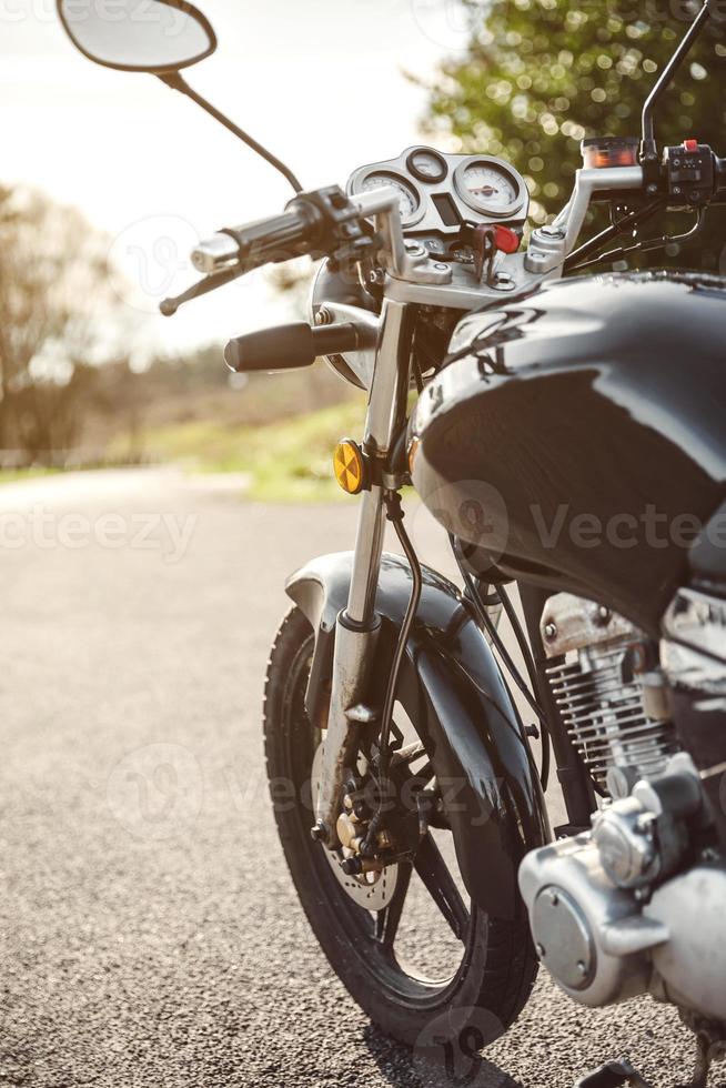 Motocicleta negra en la carretera sobre fondo de naturaleza foto