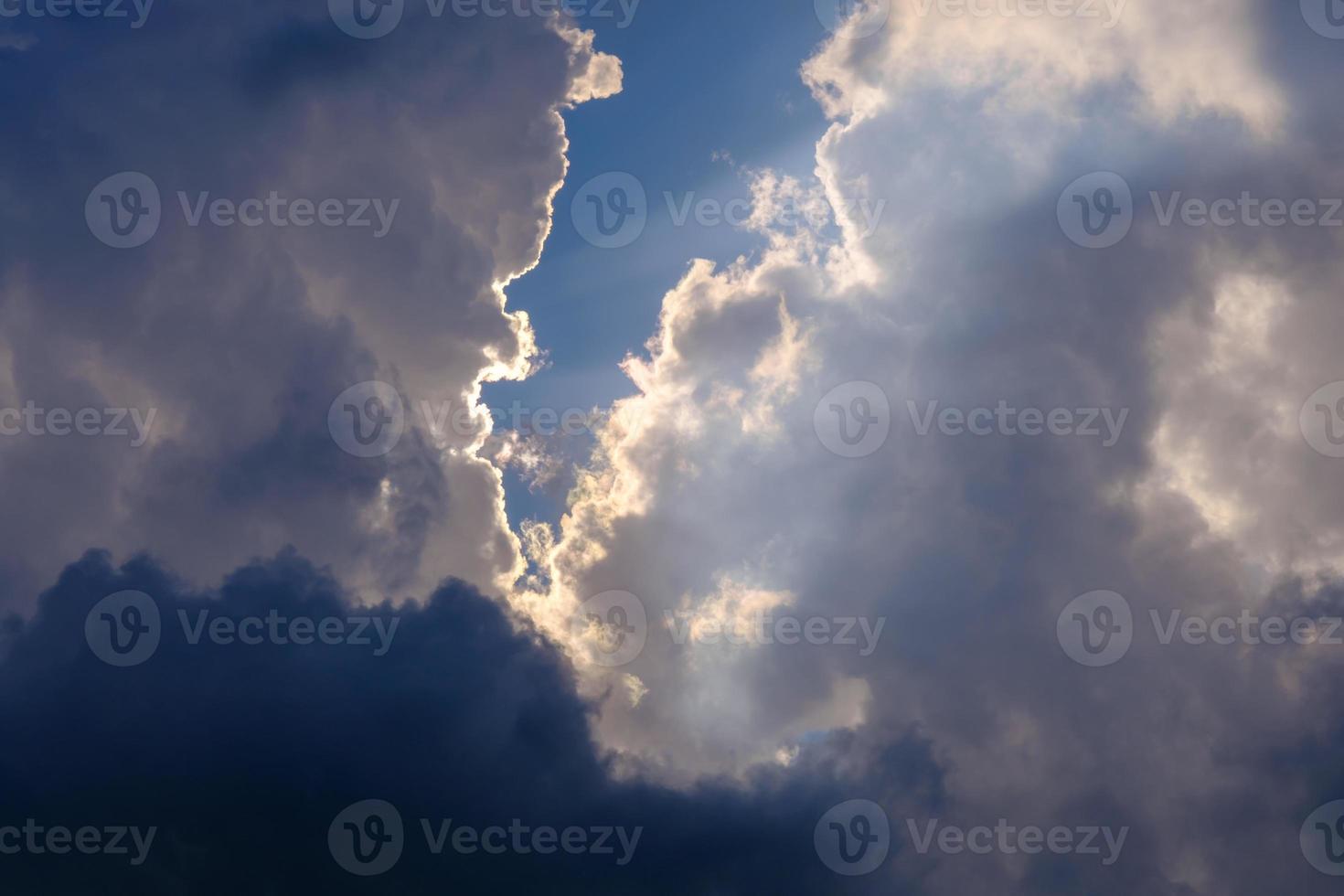 sunlight breaking through white and dark clouds in the blue sky photo