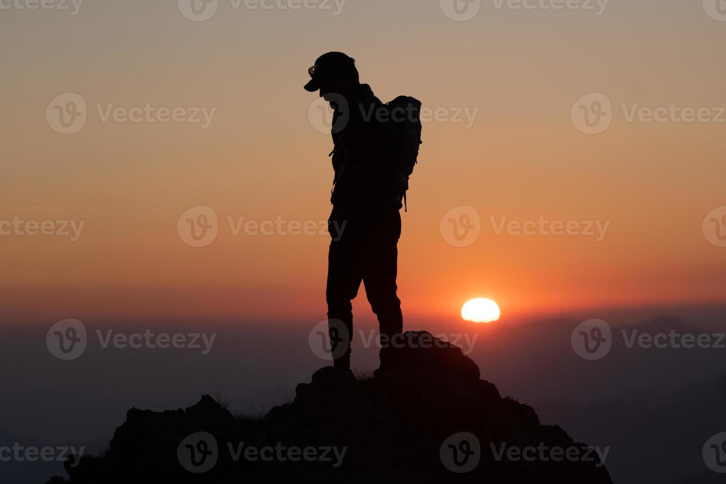 idílica puesta de sol con un alpinista en la cima foto