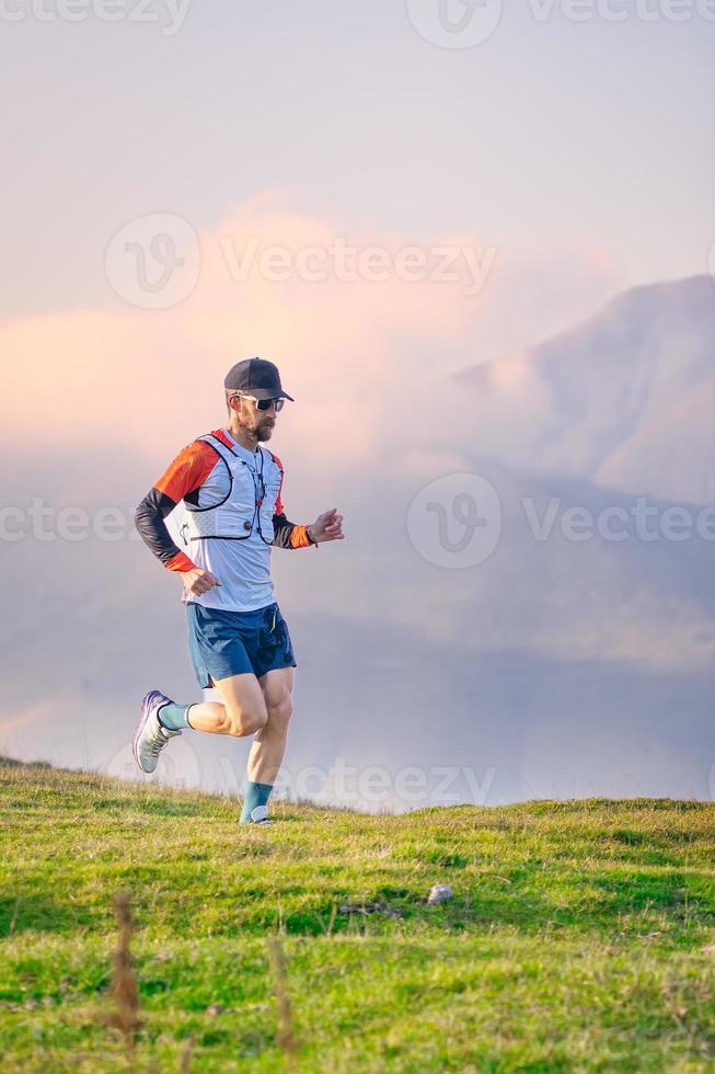 Man mountain runner trains on meadows photo