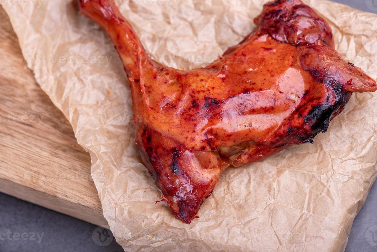 The stewed red chicken legs in the container are in a dark background photo