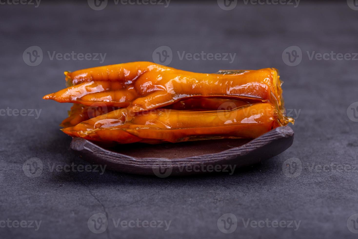 Stewed chicken feet are in the container in the dark background photo