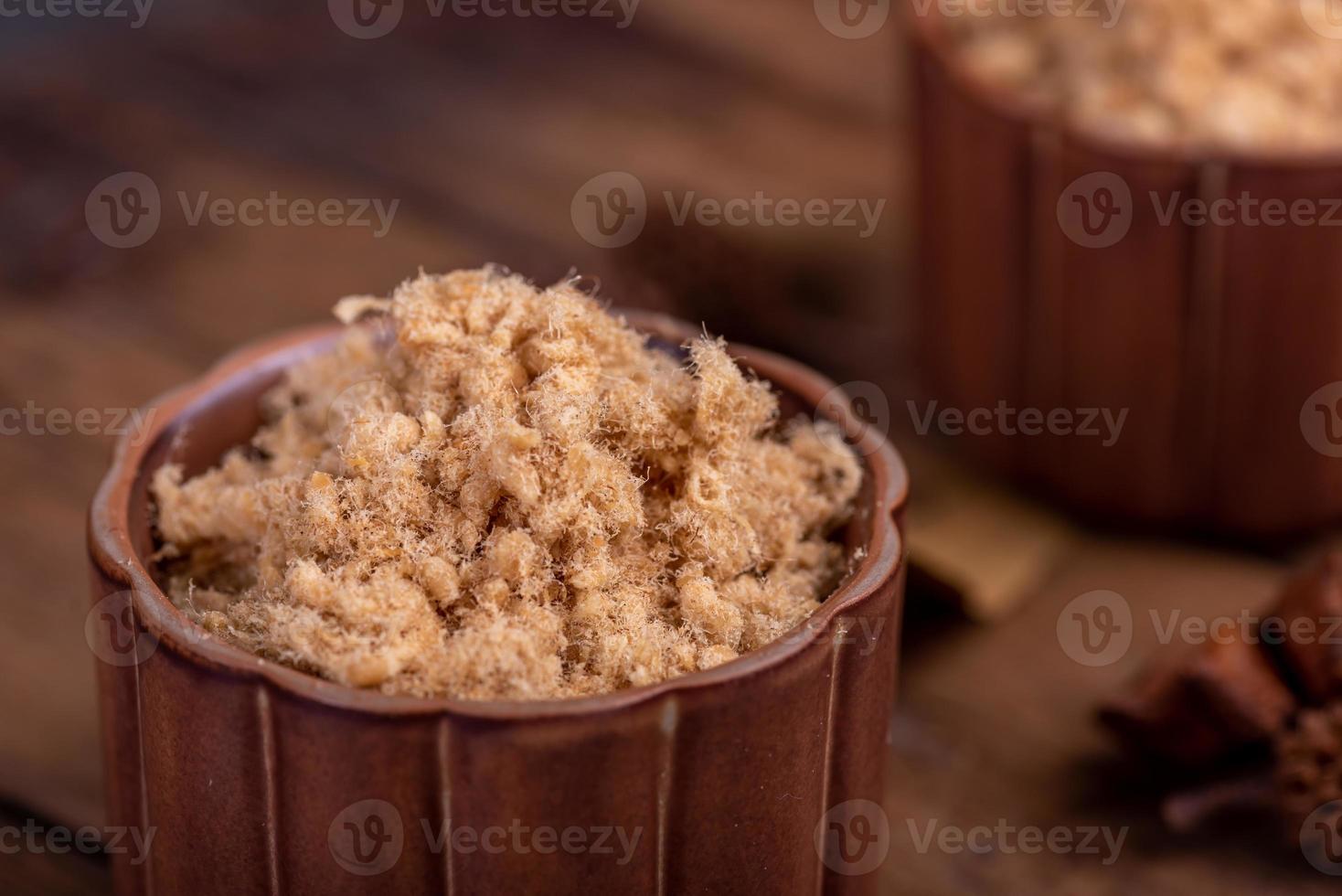 The refined meat floss is in the cup in the dark background photo