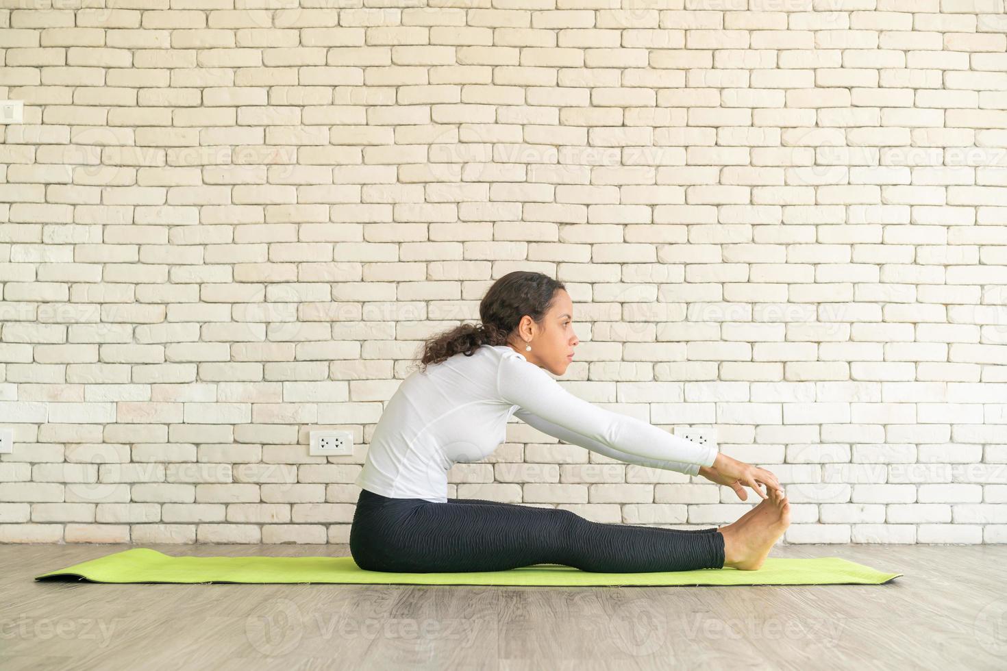 Latin woman practicing yoga on mat photo