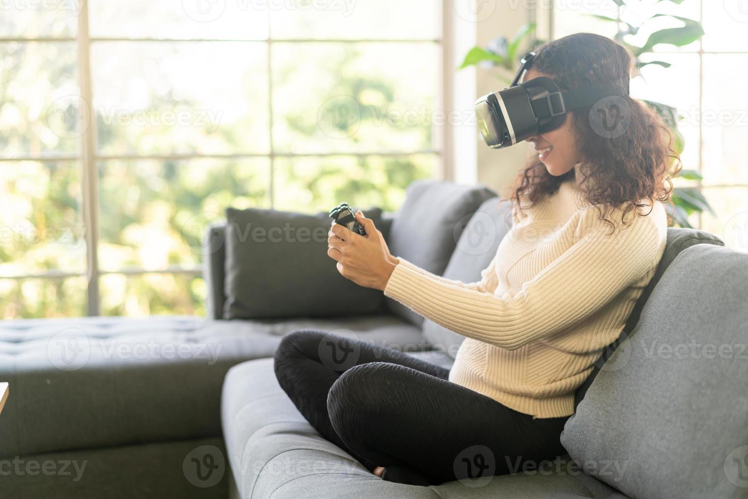 Mujer latina con un casco de realidad virtual en el sofá foto