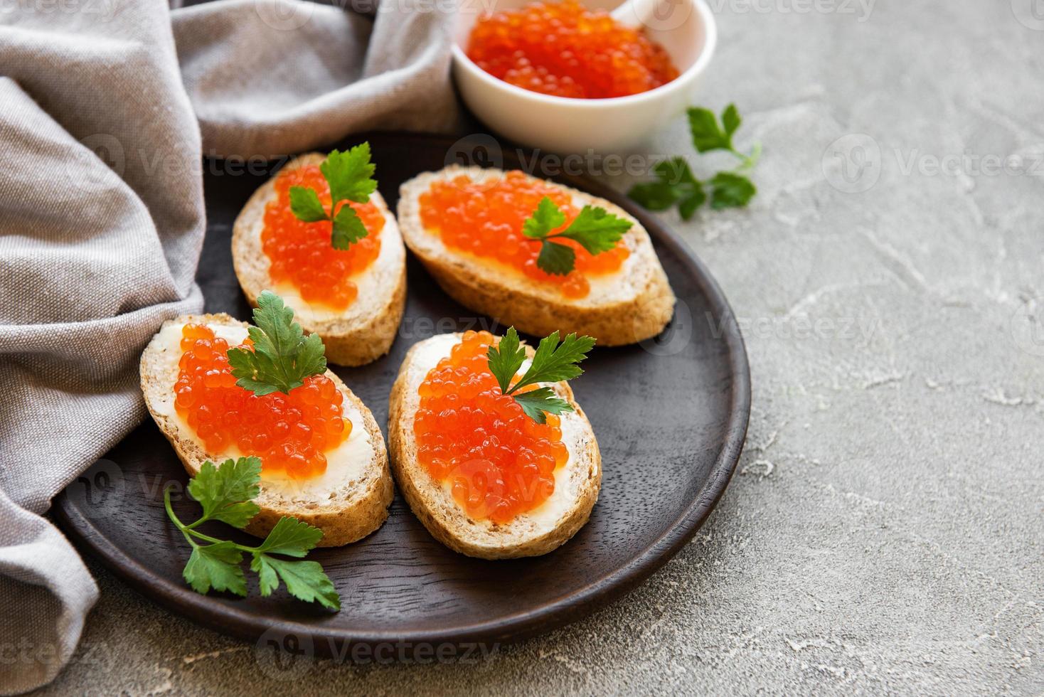 Red caviar in bowl and sandwiches photo