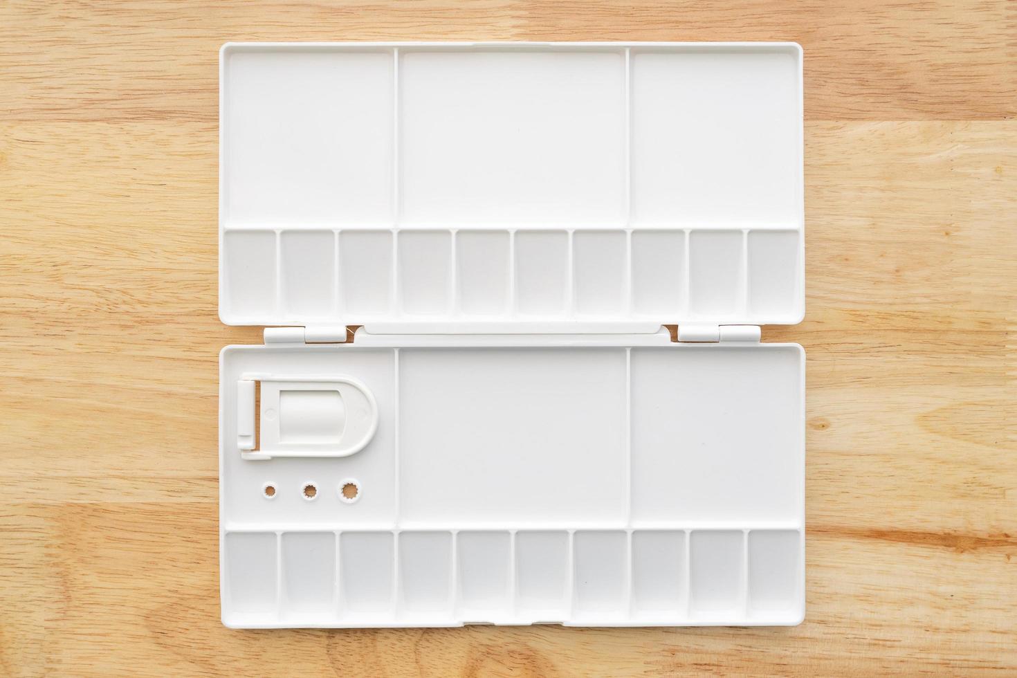White watercolor palette. Empty watercolor tray isolated on wood background. photo