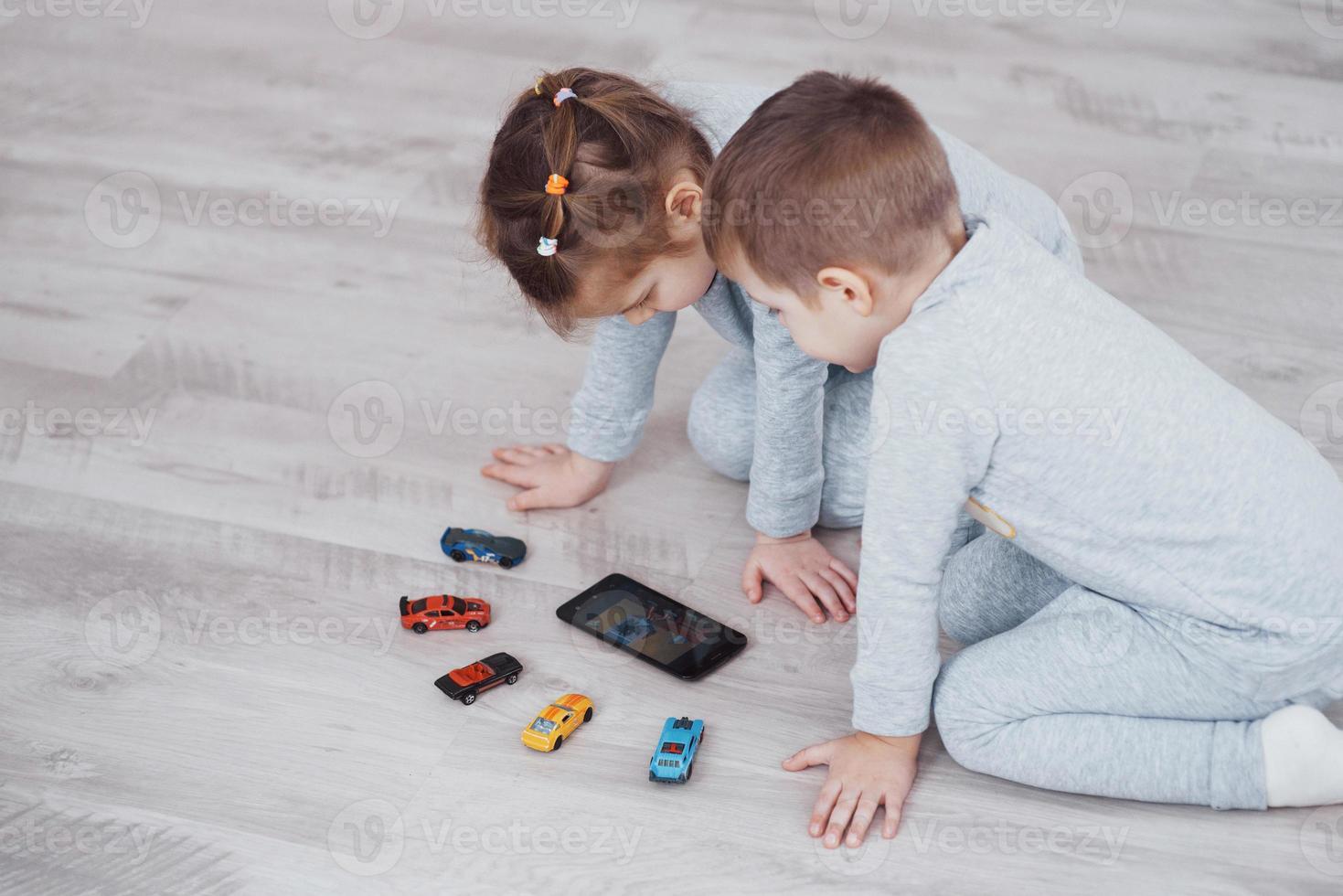 Children using digital gadgets at home. Brother and sister on pajamas watch cartoons and play games on their technology tablet photo