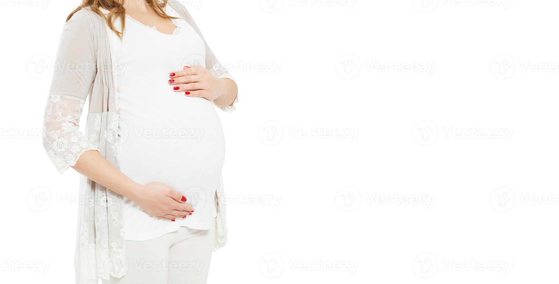 Pregnant woman holds hands on belly on a white background. Pregnancy, maternity, preparation and expectation concept. Close-up, copy space, indoors. Cropped image. photo