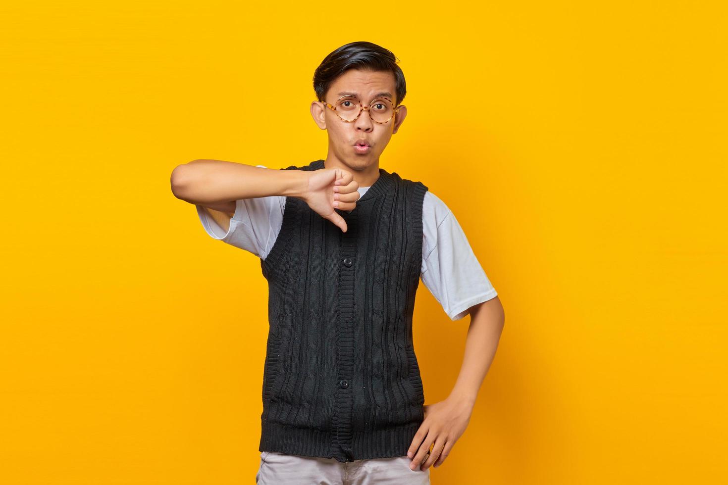young asian man looking unhappy and angry showing rejection with thumbs down gesture photo