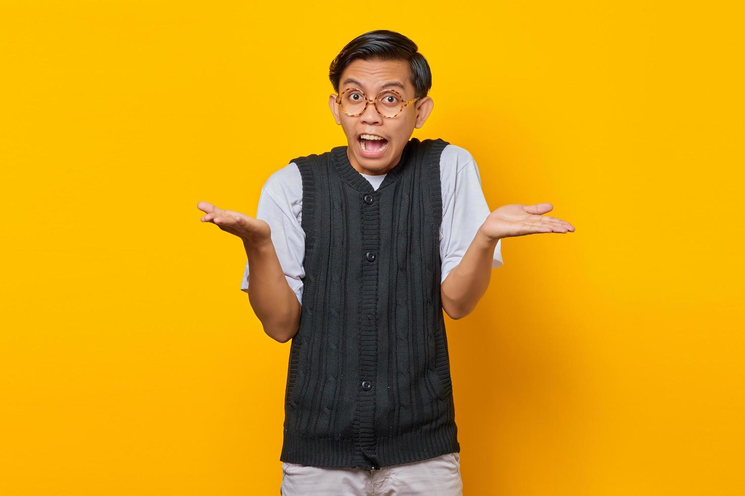 Portrait of asian man surprised with confused and displeased expression on yellow background photo