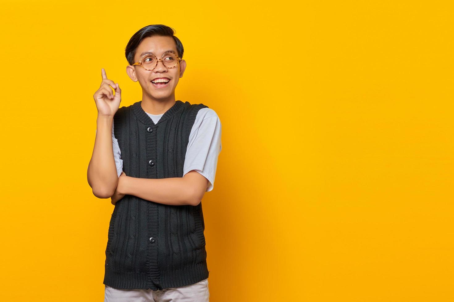 Excited handsome young man raising finger and having creative idea on yellow background photo