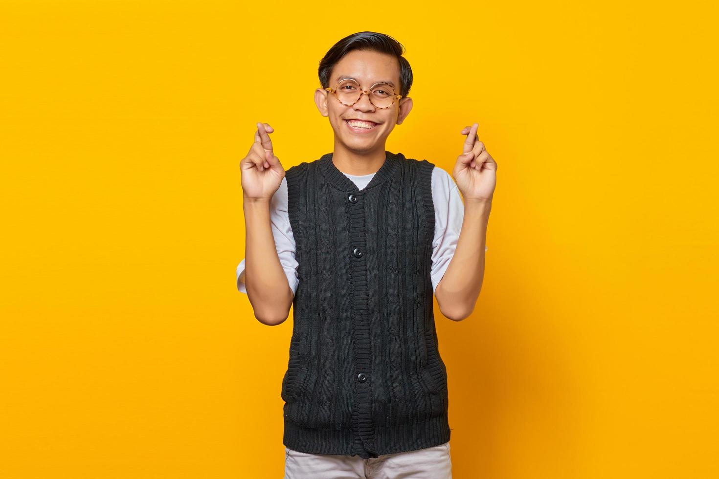retrato, de, sonriente, joven, asiático, hombre, uniforme, gesticular, dedo, cruzado, sobre, fondo amarillo foto
