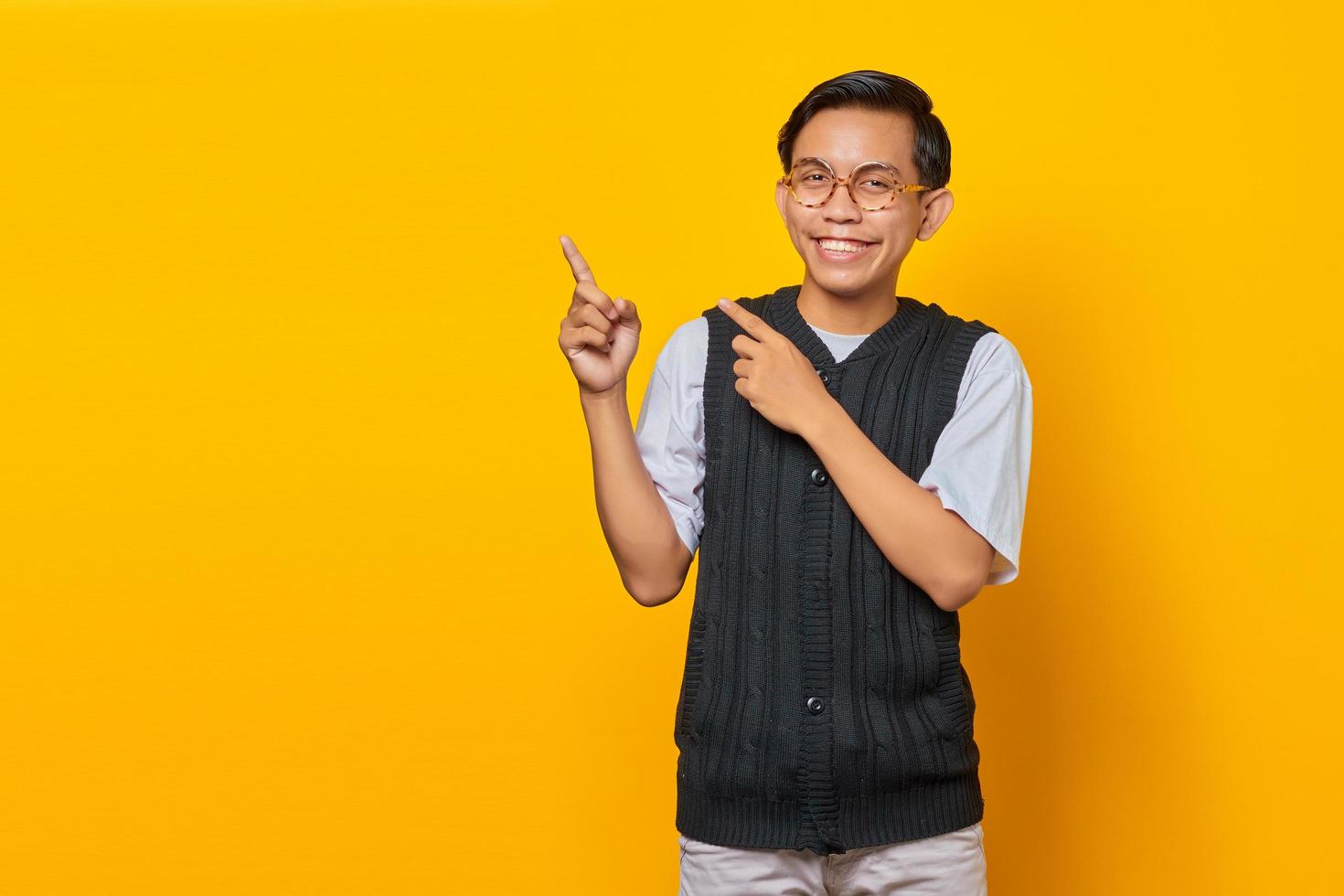 Portrait of smiling young Asian man pointing to copy space with finger photo