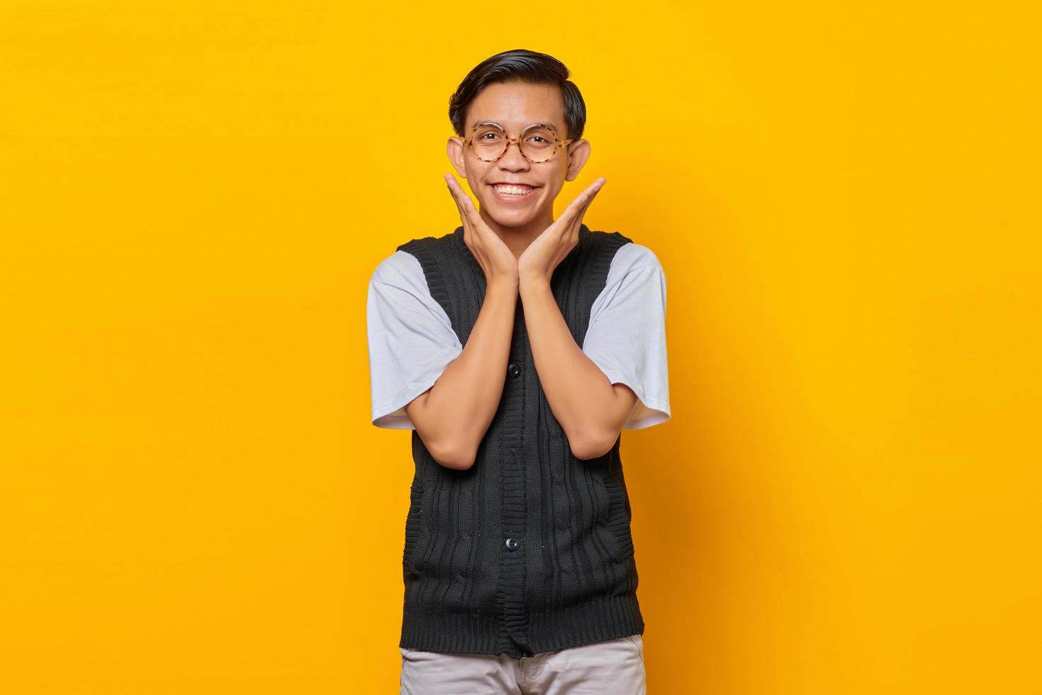 Retrato de alegre joven asiático mirando a la cámara sobre fondo amarillo foto