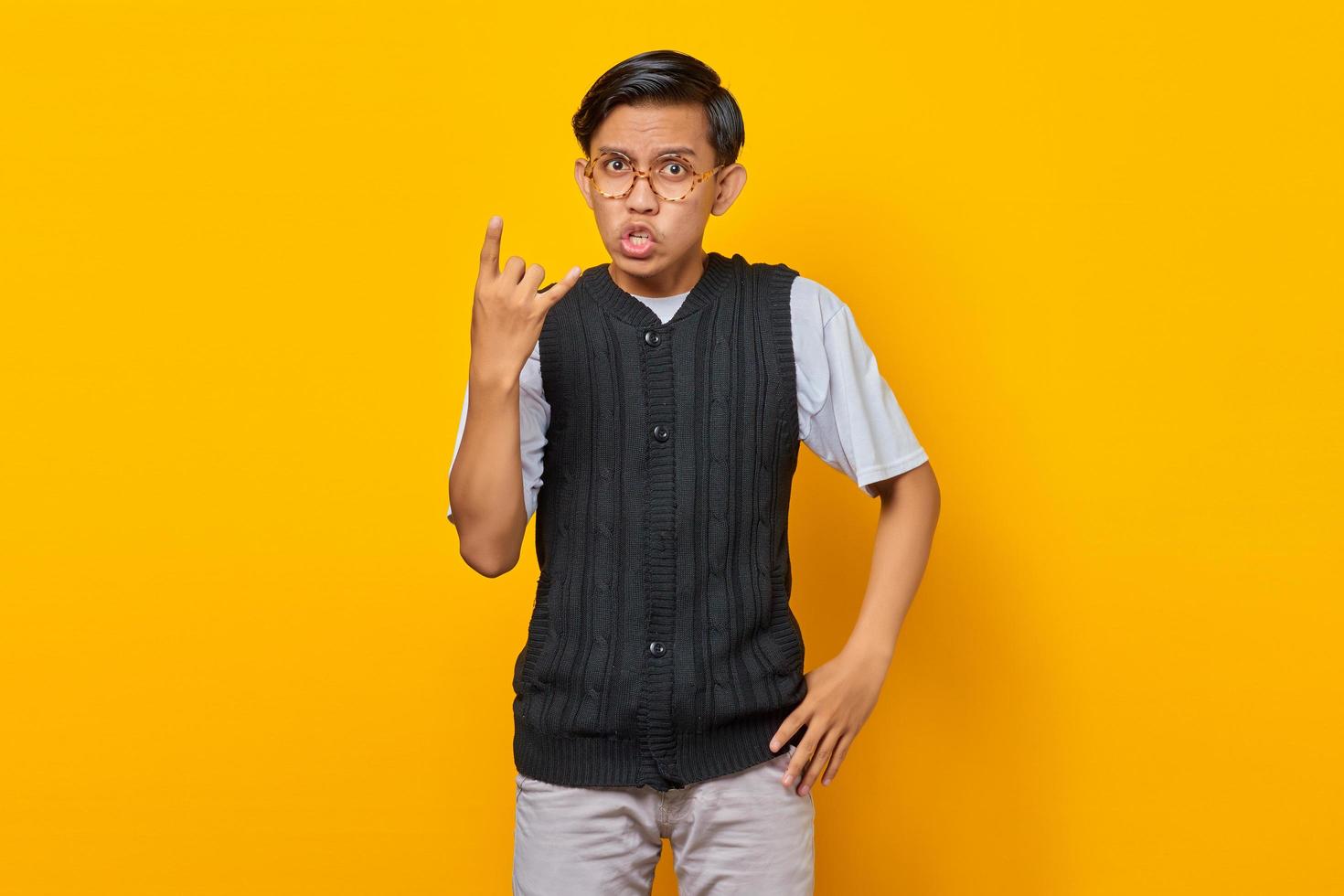 Portrait of young asian man wearing casual clothes screaming with crazy expression doing rock symbol with hands up photo