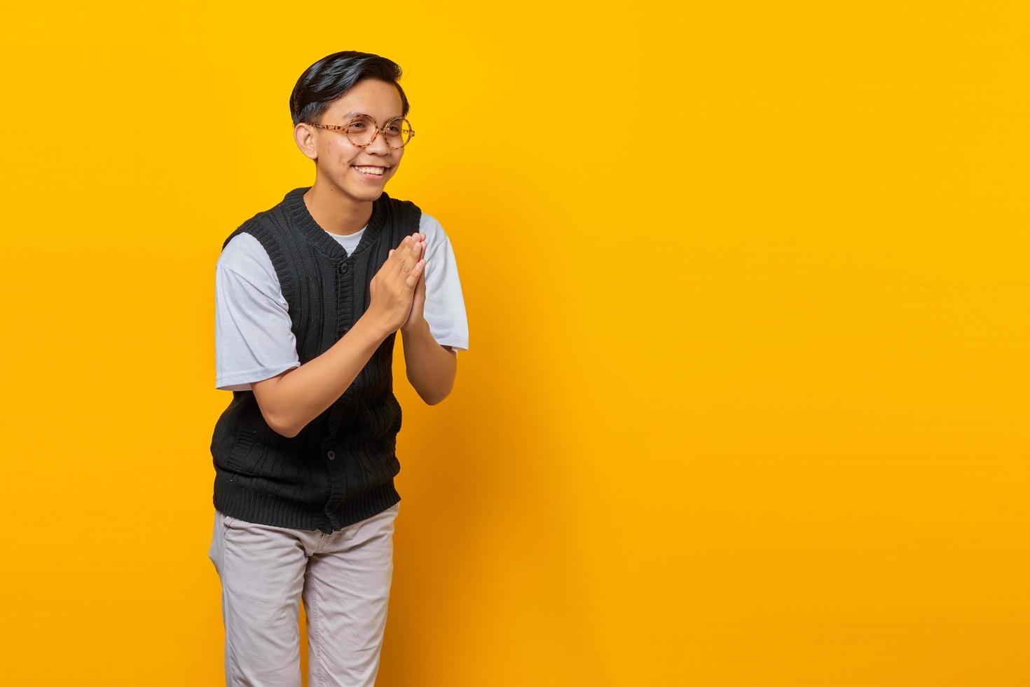 retrato, de, asiático, apuesto, joven, saludo, con, grande, sonrisa, en, el suyo, cara, en, fondo amarillo foto