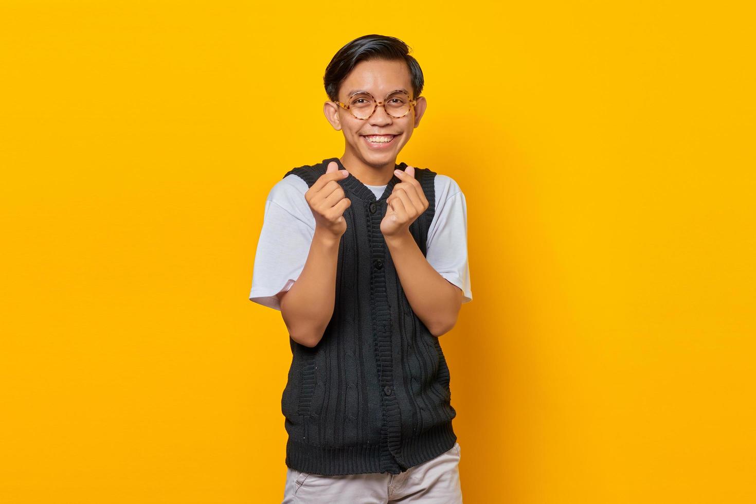 retrato, de, sonriente, joven, asiático, hombre, actuación, dedo, corazones, encima, fondo amarillo foto