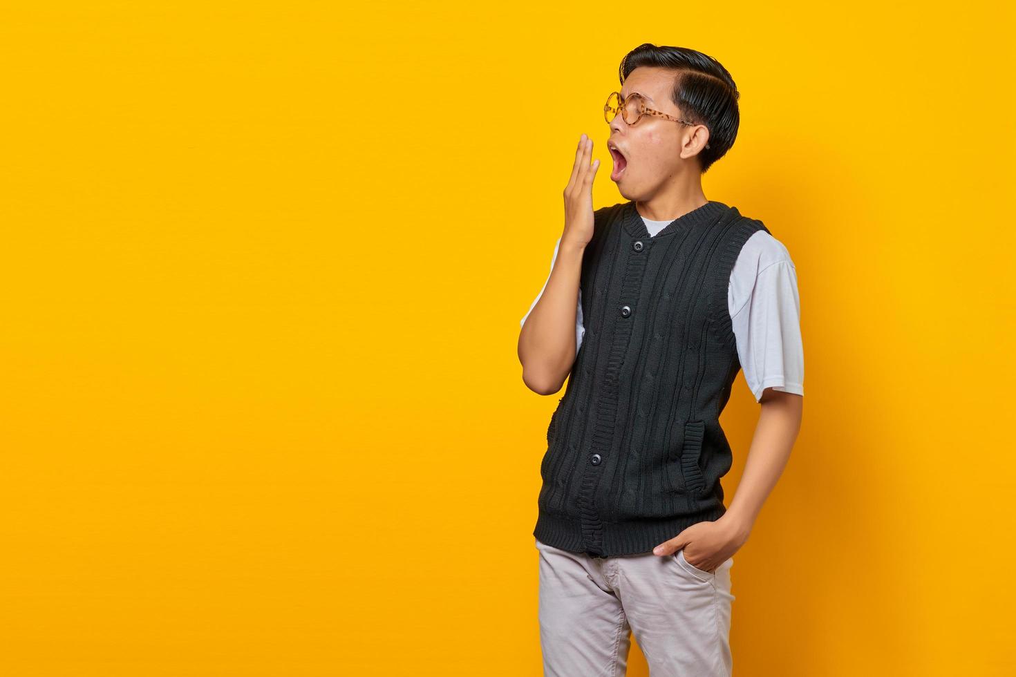 Portrait of handsome young Asian man feeling sleepy and covering mouth with hand photo