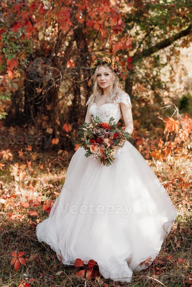 chica rubia en un vestido de novia en el bosque de otoño foto