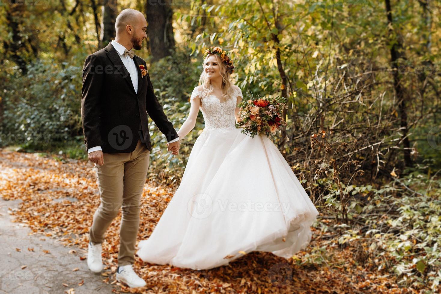 walk of the bride and groom through the autumn forest photo