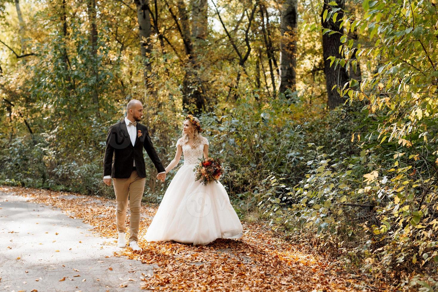 walk of the bride and groom through the autumn forest photo