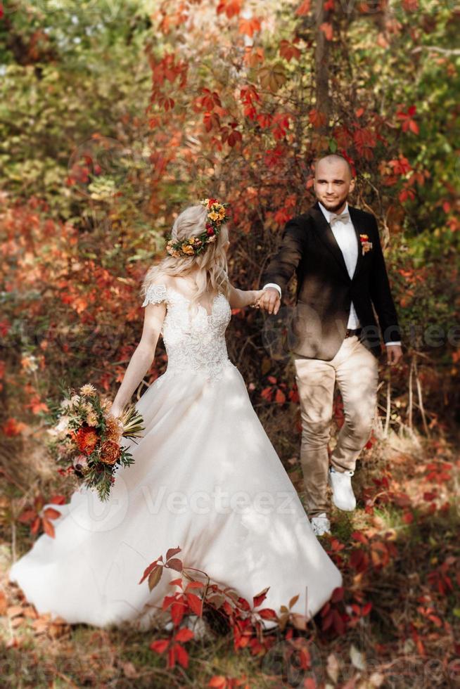 walk of the bride and groom through the autumn forest photo
