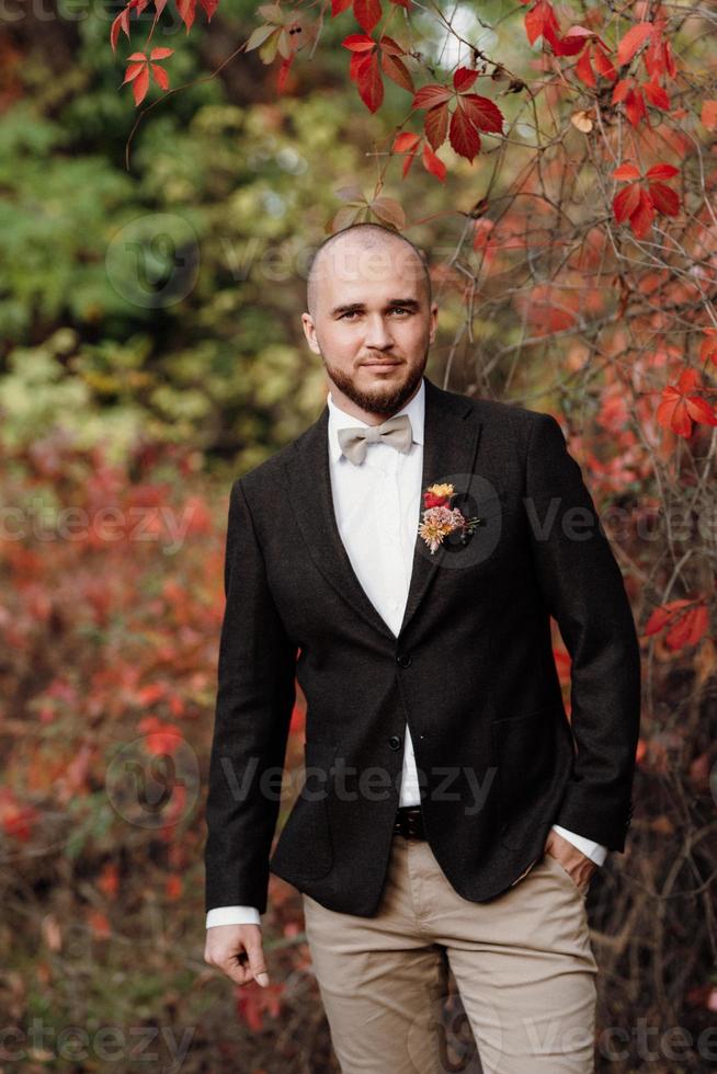 Chico calvo con barba en una chaqueta marrón sobre un fondo de uvas rojas foto