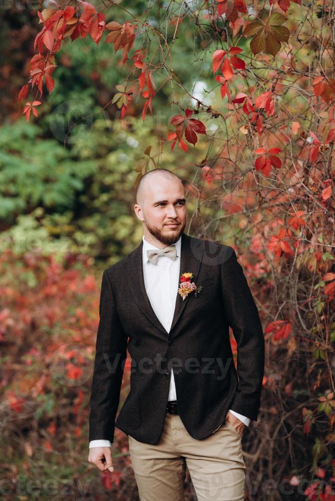 bald bearded guy in a brown jacket on a background of red grapes photo