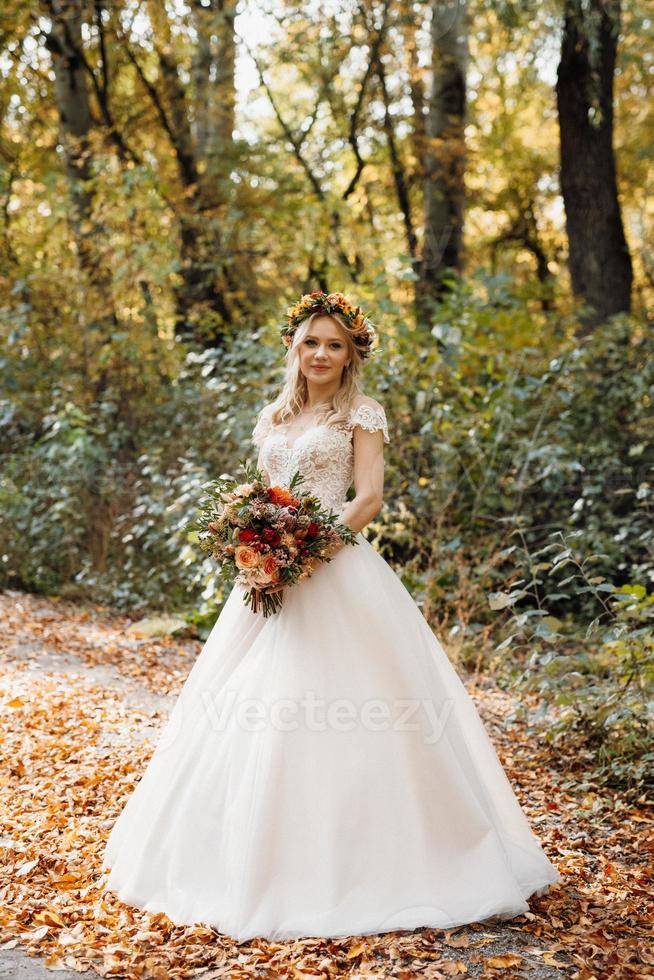 chica rubia en un vestido de novia en el bosque de otoño foto