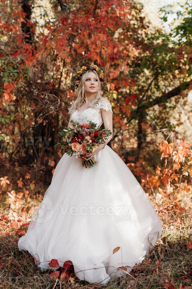 chica rubia en un vestido de novia en el bosque de otoño foto