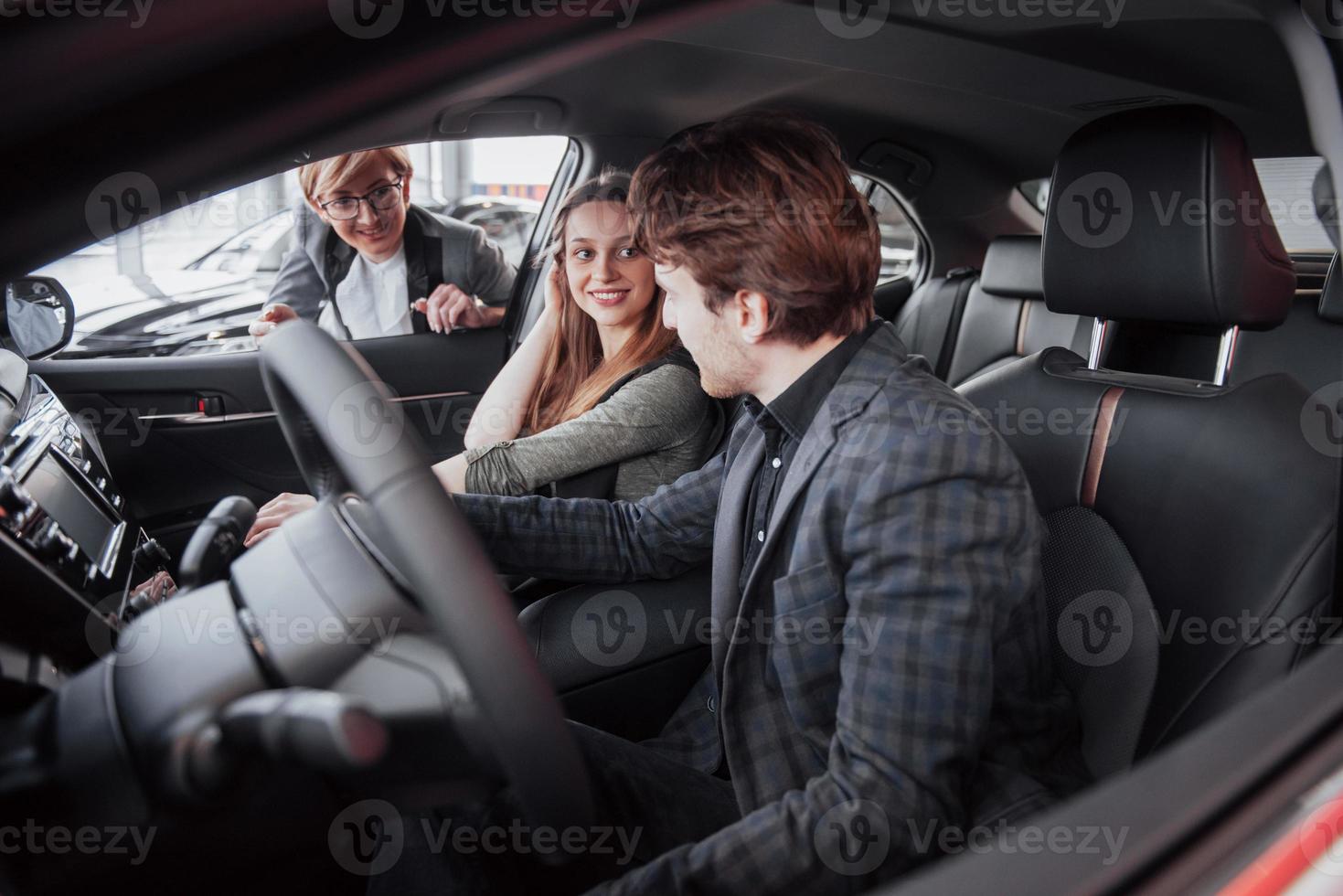 feliz hermosa pareja está eligiendo un coche nuevo en el concesionario foto