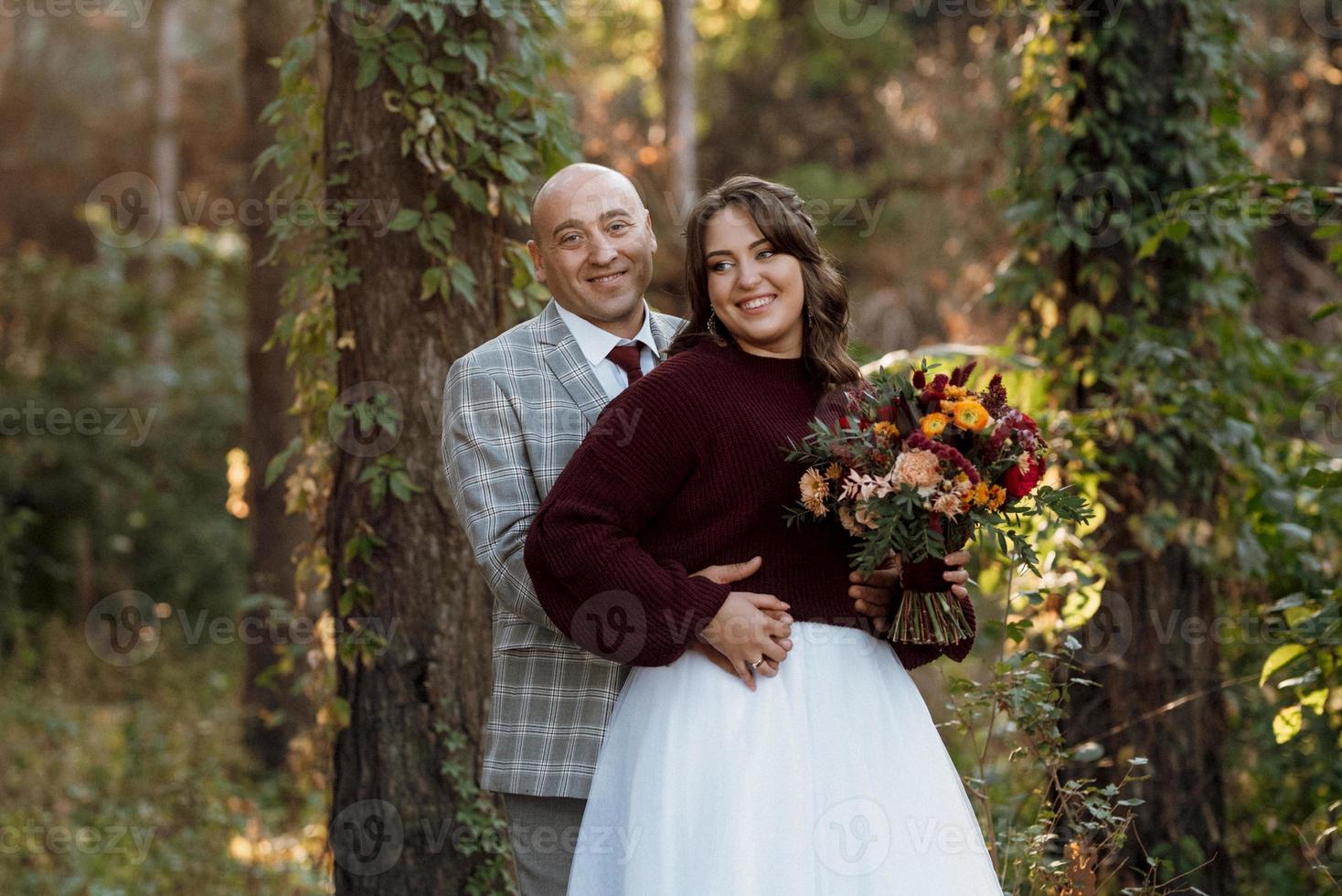 walk of the bride and groom through the autumn forest photo