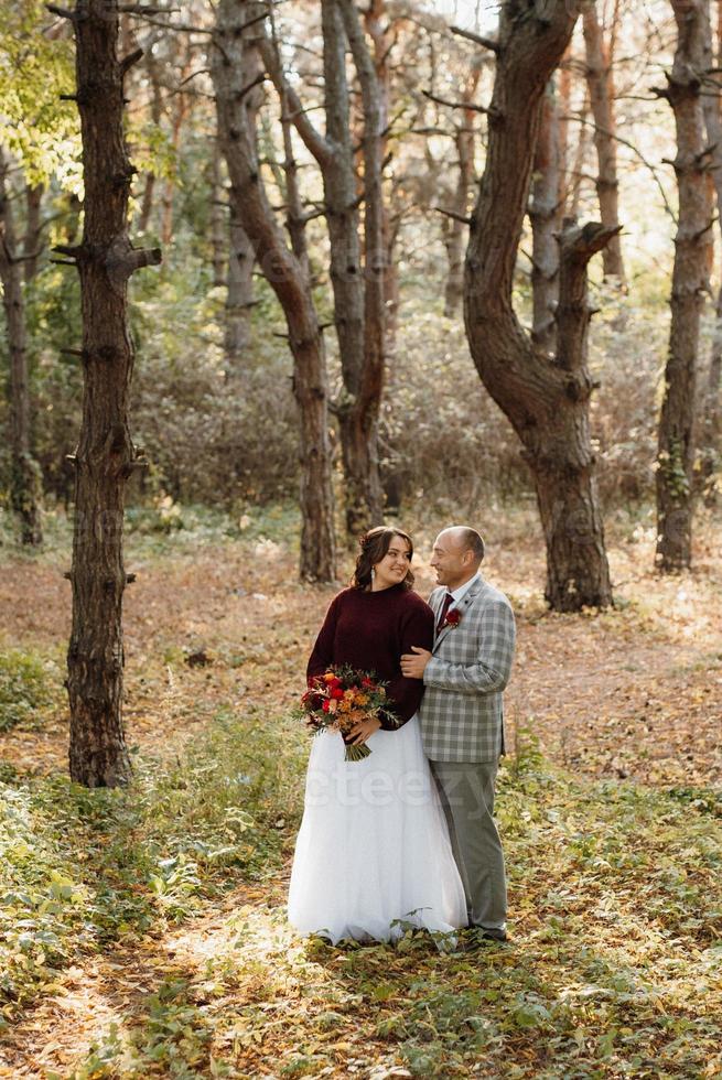 walk of the bride and groom through the autumn forest photo