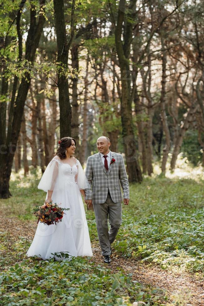 walk of the bride and groom through the autumn forest photo