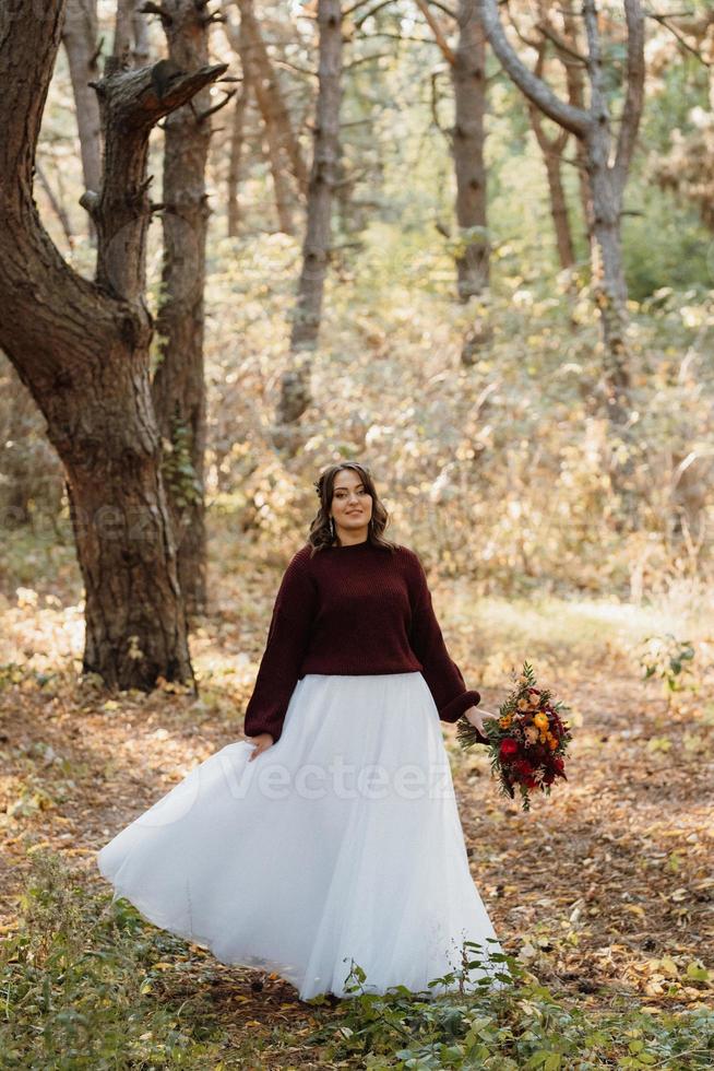 girl in a wedding dress in the autumn forest photo