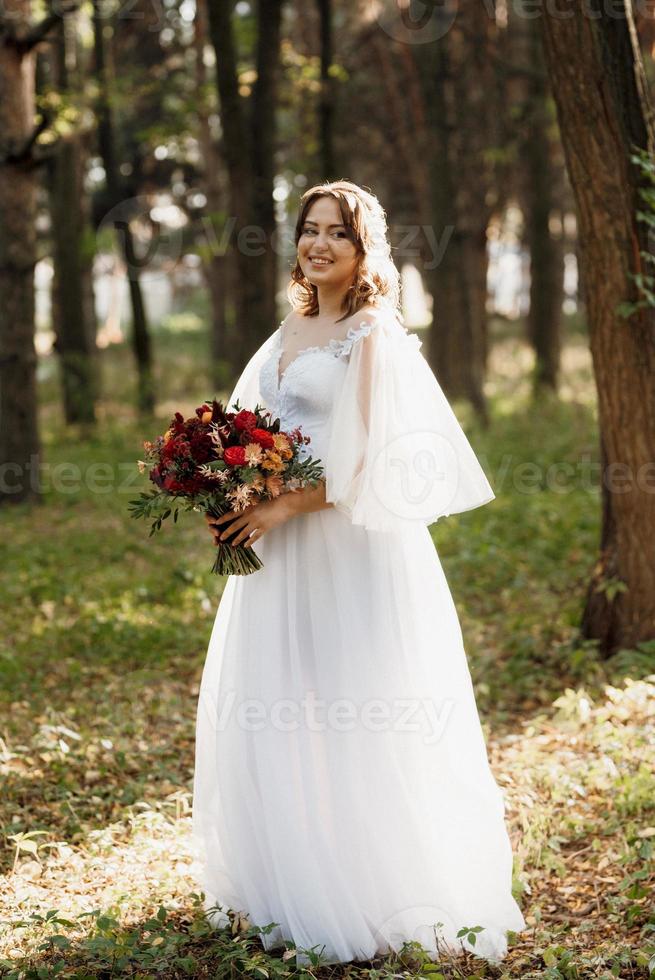 girl in a wedding dress in the autumn forest photo