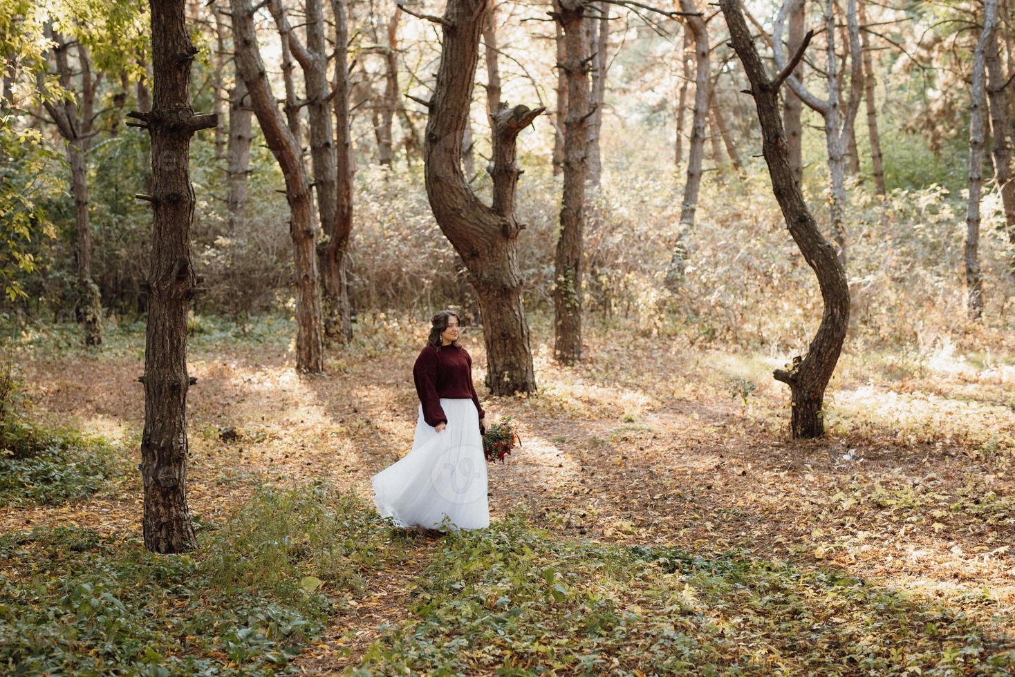 niña en un vestido de novia en el bosque de otoño foto