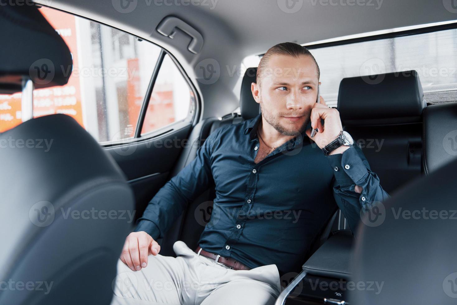 Un hombre de negocios moderno habla por teléfono en la parte trasera del coche. foto