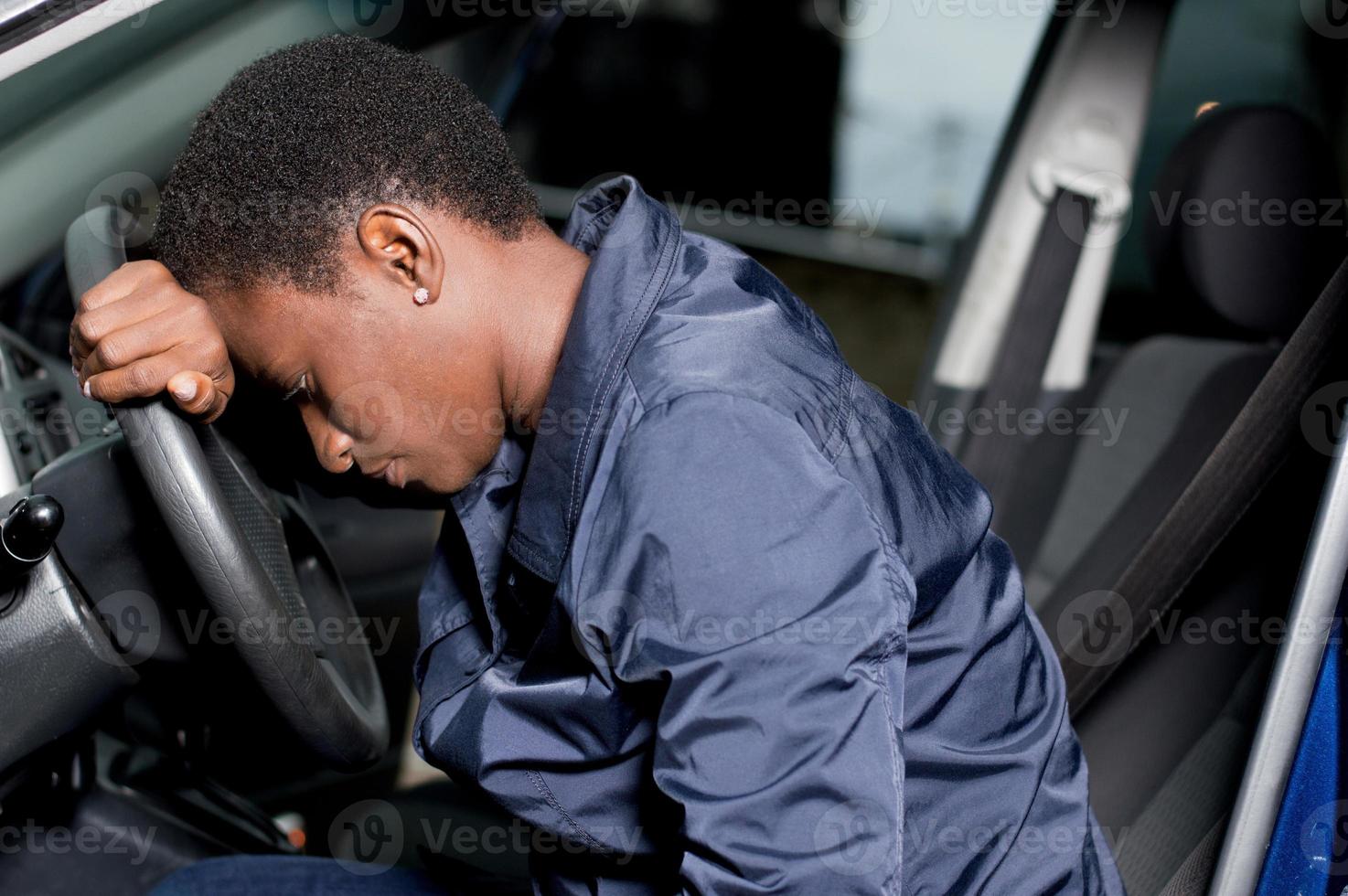 mecánico joven sentado al volante de un coche. foto