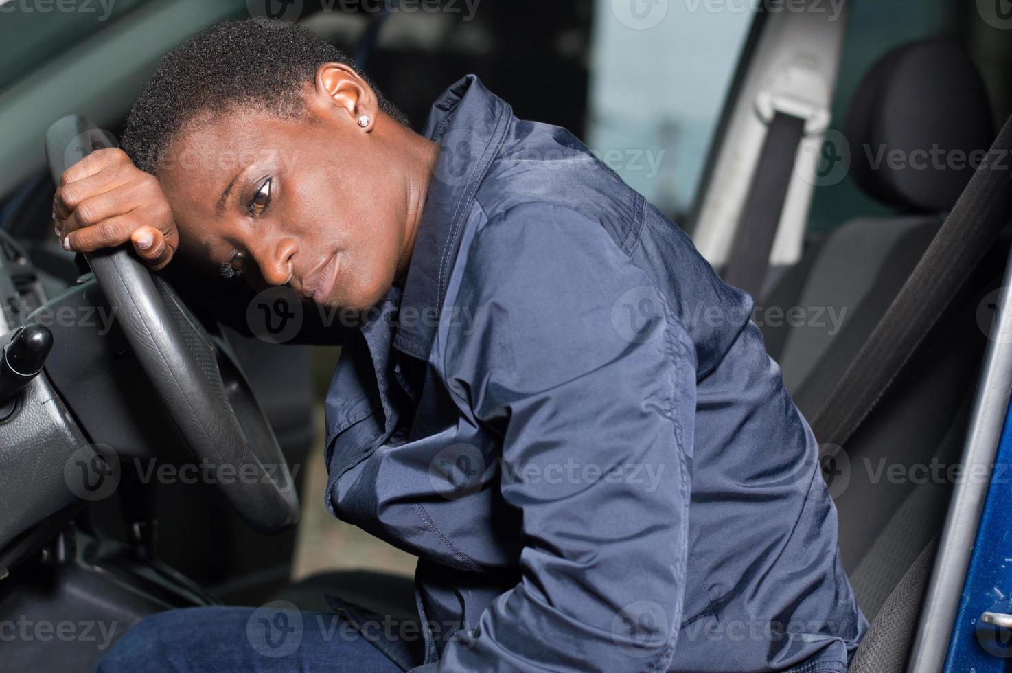 mecánico joven sentado al volante de un coche. foto